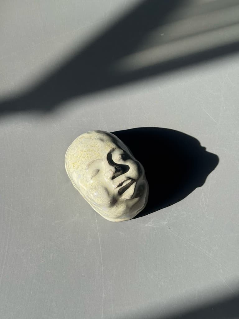 Lille keramikskulptur af et ansigt med grøn glasur