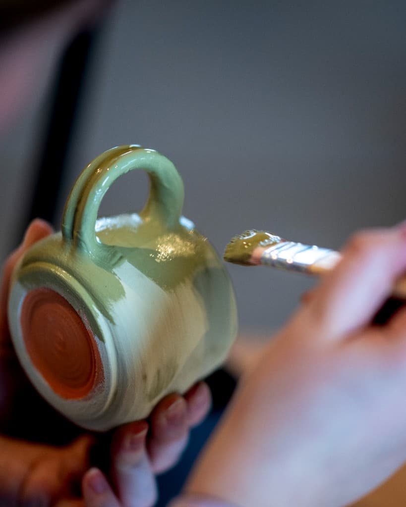 Glasering af en hånddrejet kop med pensel