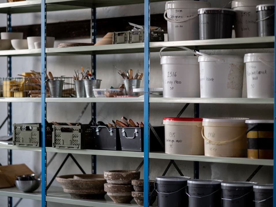 Hylder med spande og materialer i værkstedet